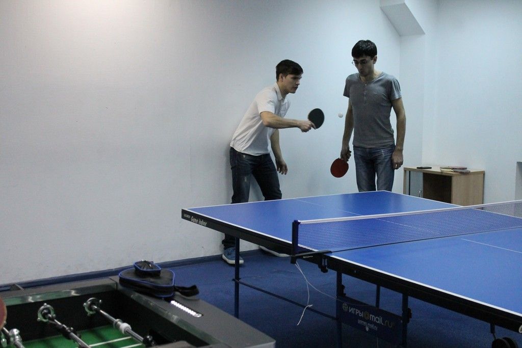 In this image I can see two are playing the game table tennis.