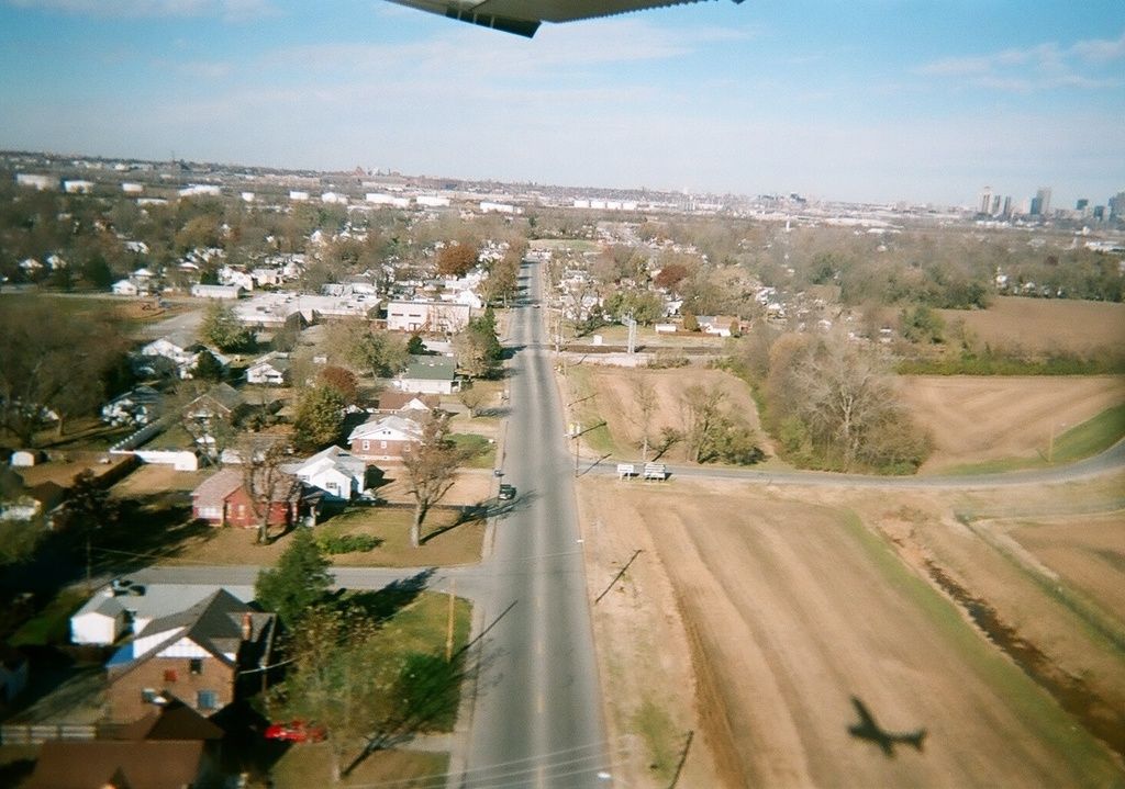 In this picture there is a top view of the town. In the front we can see some trees and small shed...