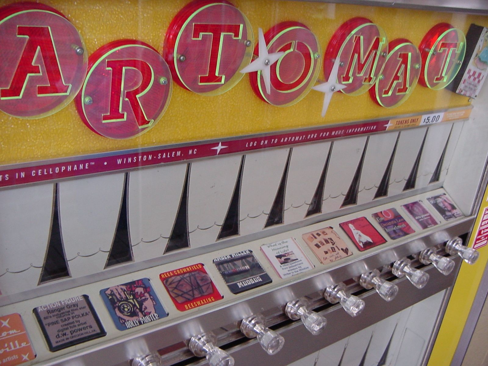 The image shows a close up of a slot machine with a sign on it. The machine has several buttons and...