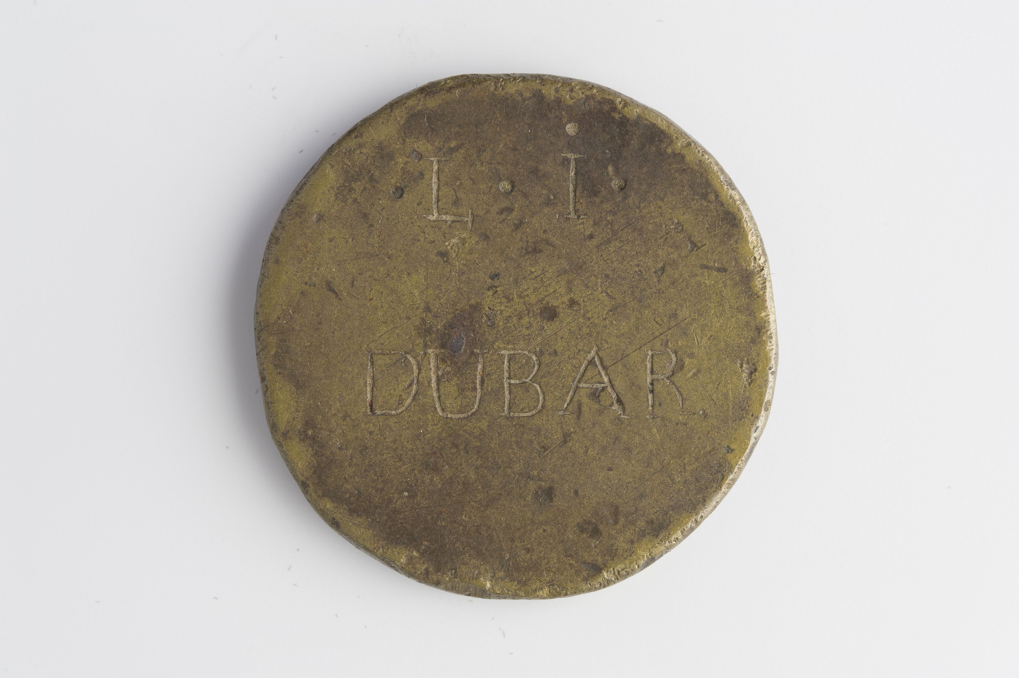 The image shows a gold coin with the word "Dubai" inscribed on it against a white background.