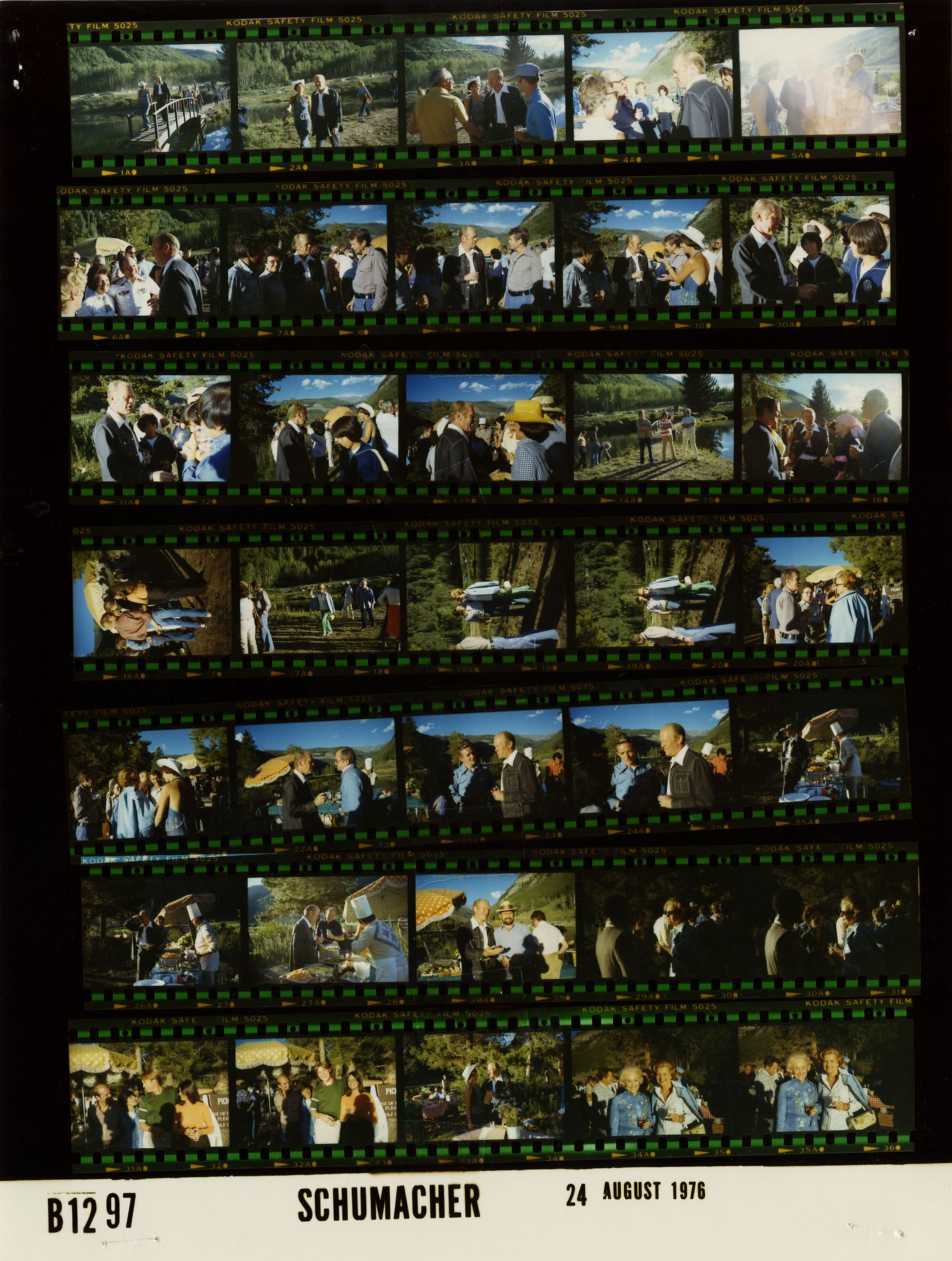 The image shows a black and white photo of a group of people standing in front of a film strip. The...