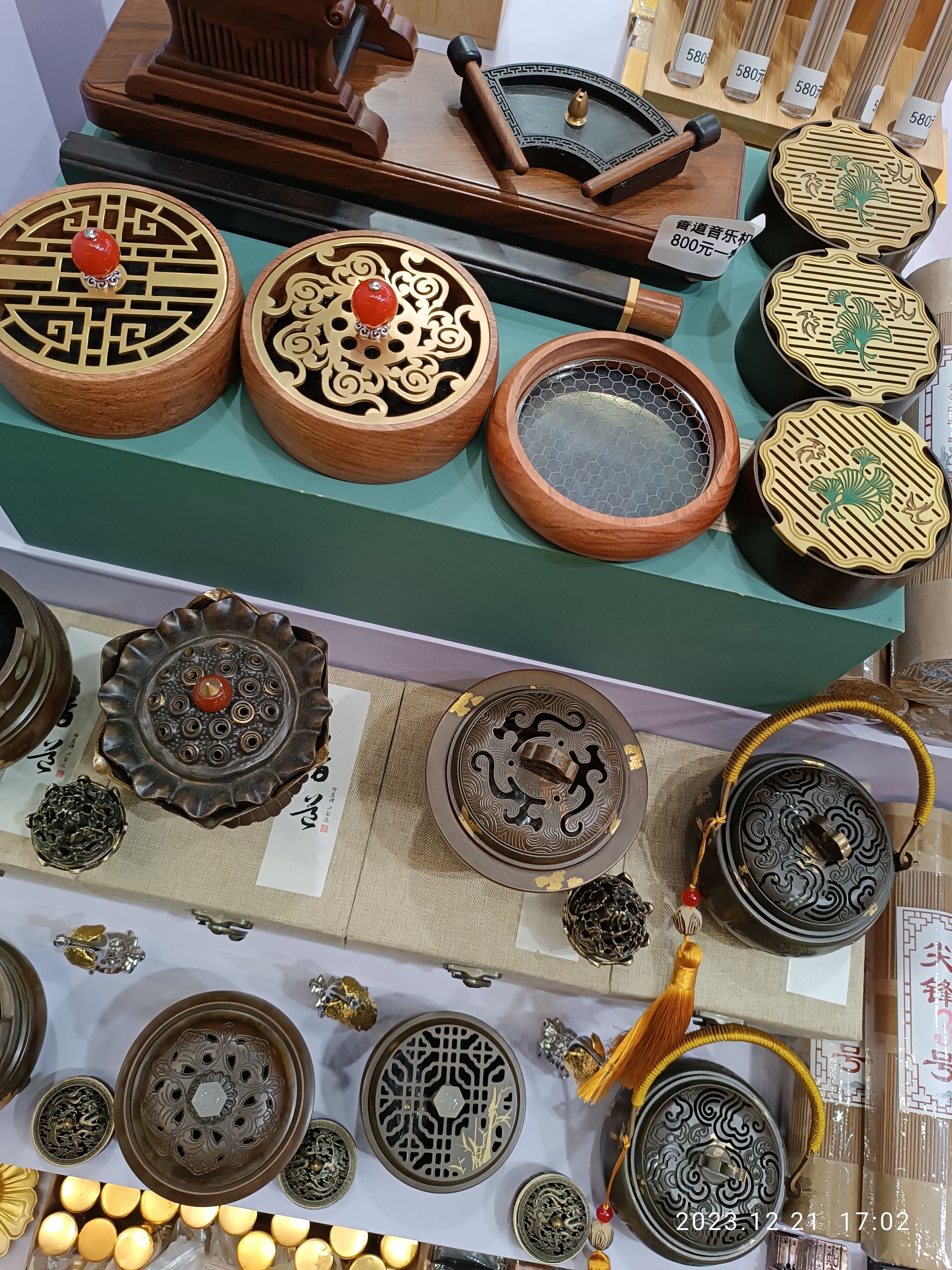 The image shows a table topped with lots of different types of Chinese incense burners, boxes, and...