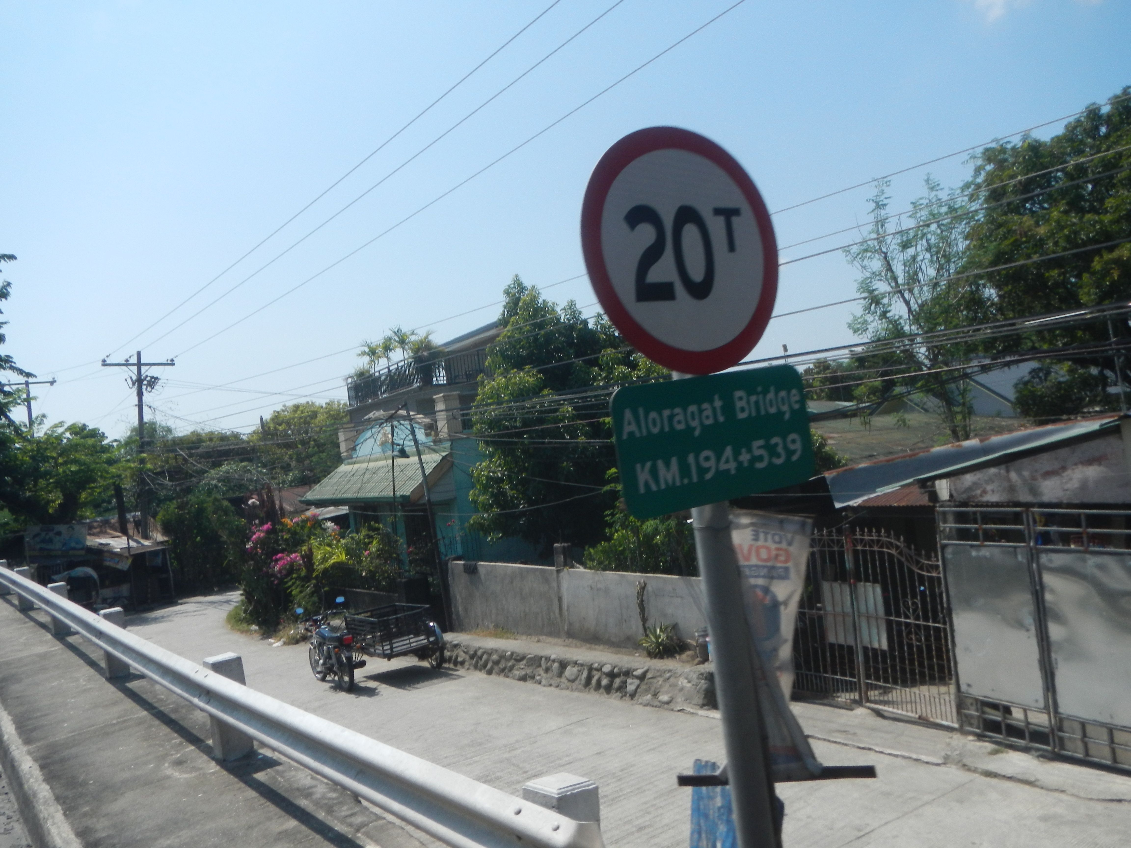 The image shows a road with a speed limit sign on the side of it. There are vehicles driving on the...