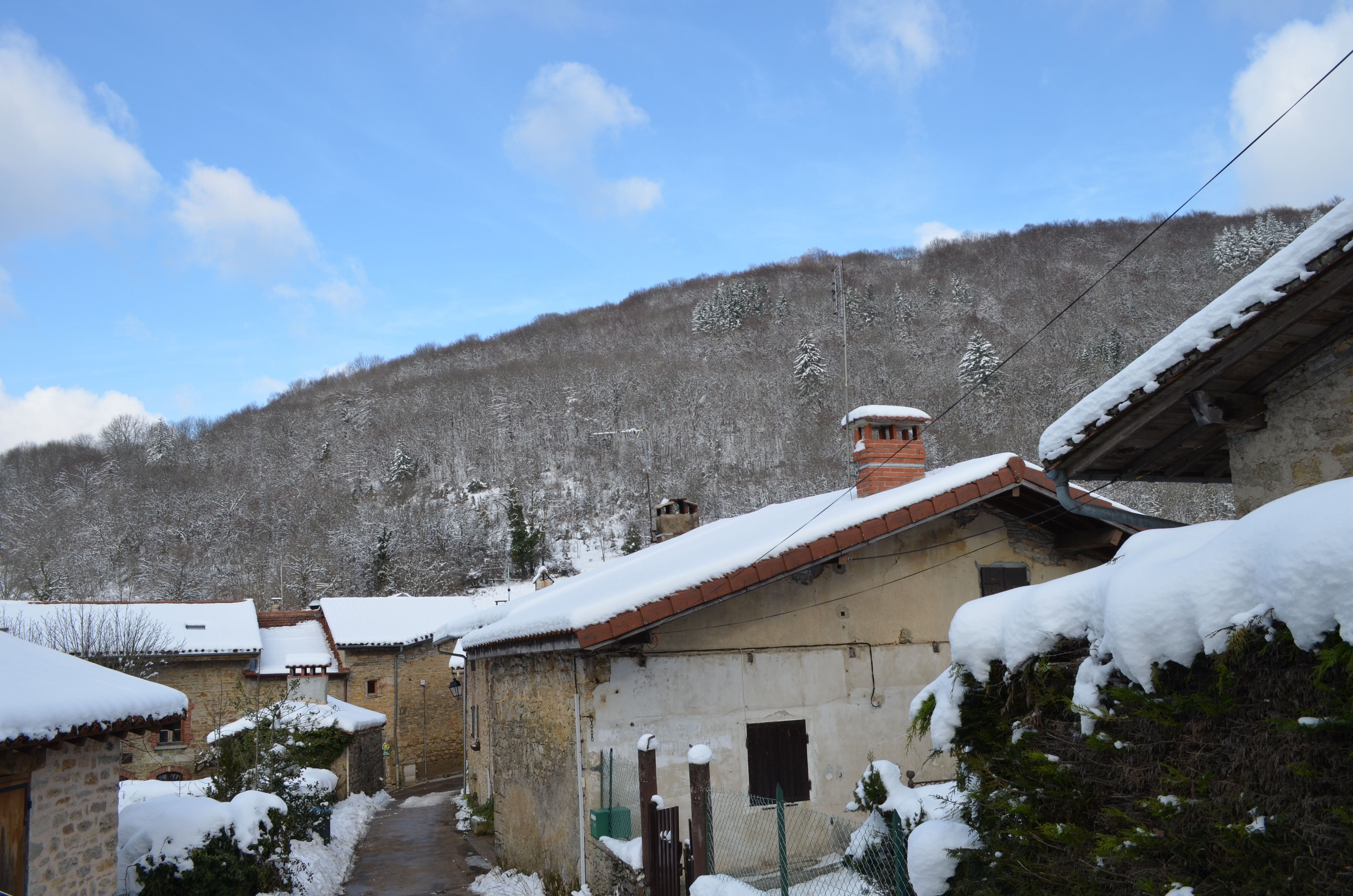 The image shows a picturesque winter scene of a small village nestled in the mountains, with...