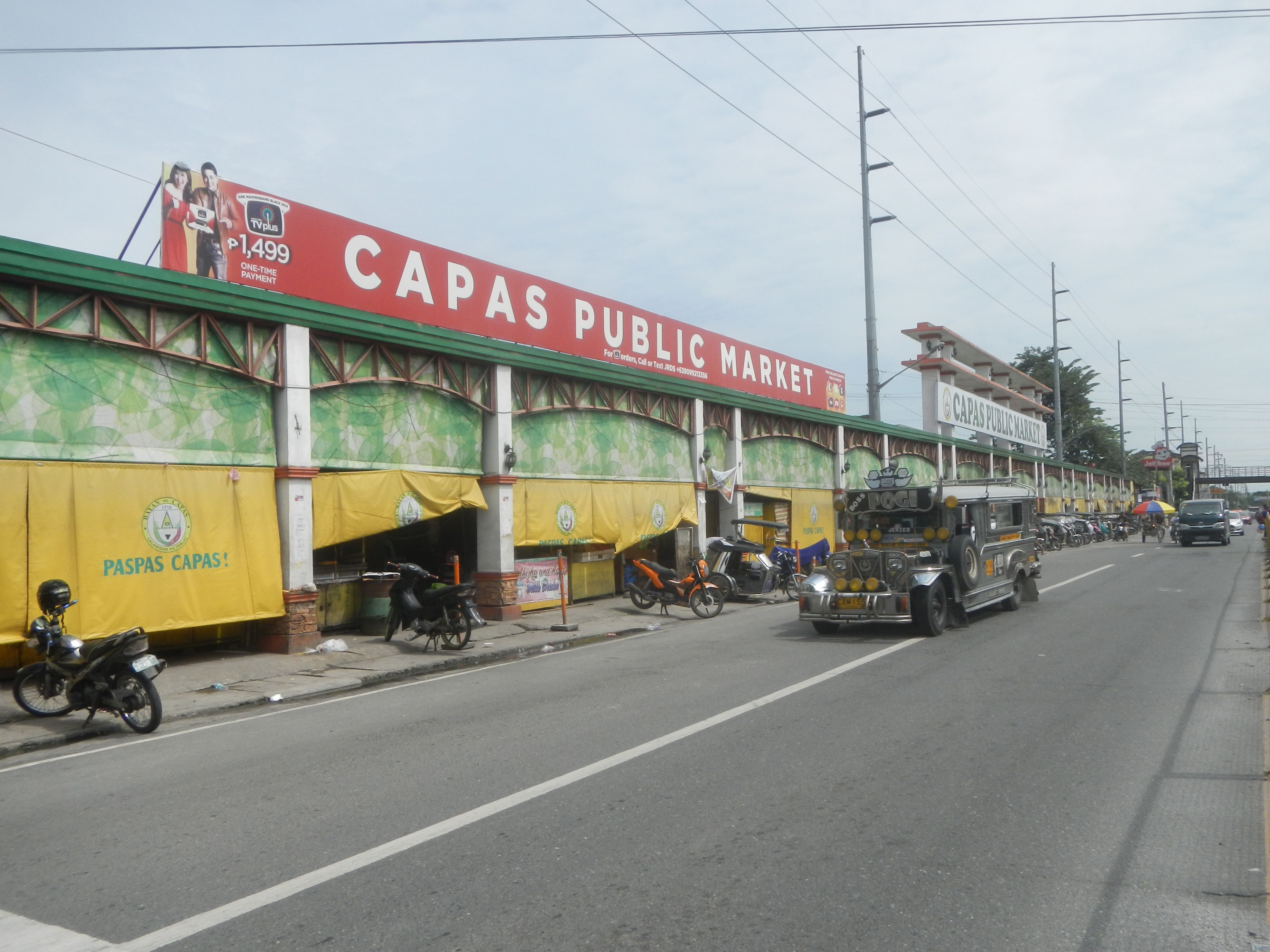 The image shows a bustling city street with vehicles on the road, a footpath on the right side,...