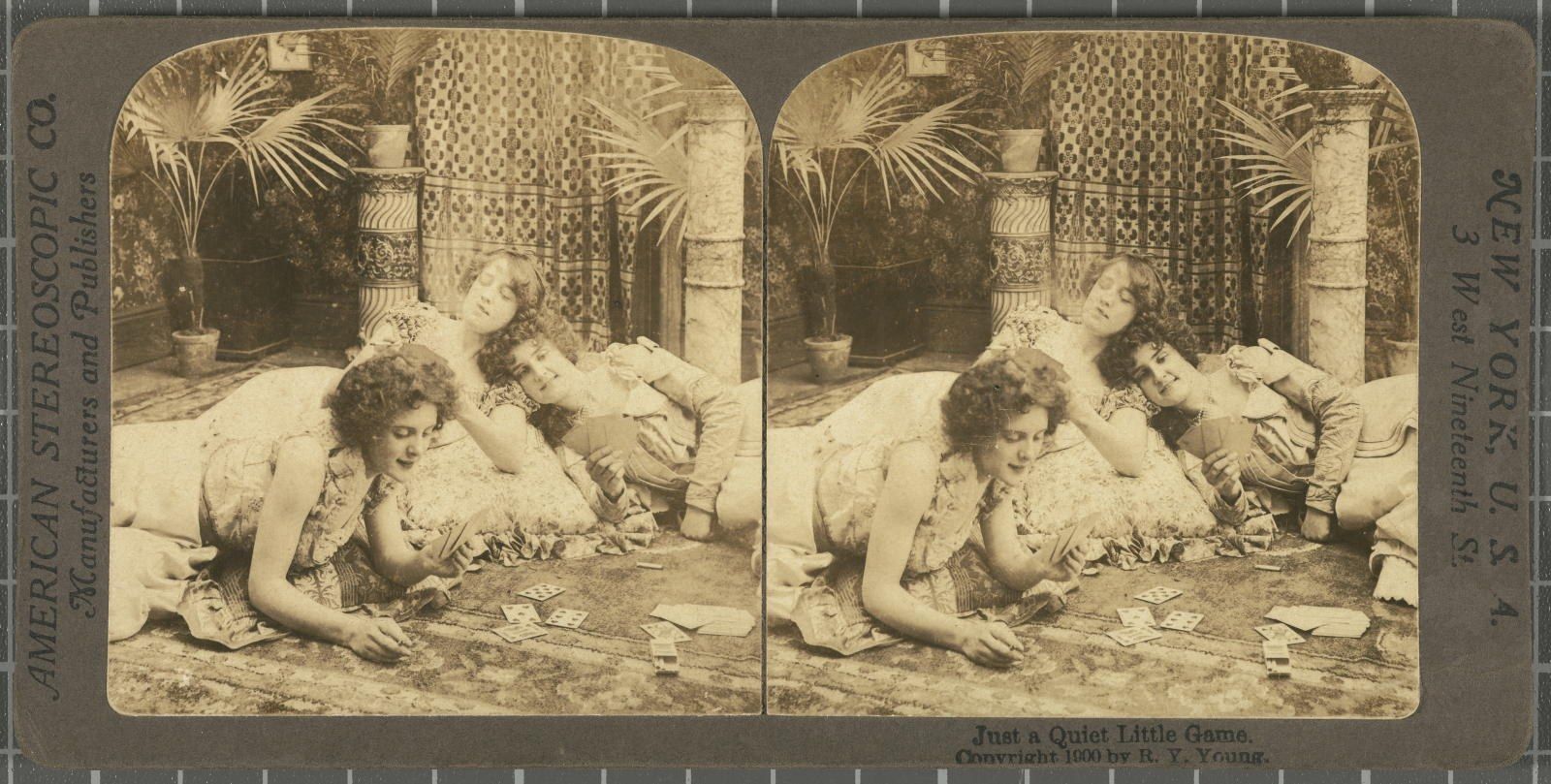 The image shows a group of women laying on the ground playing cards, surrounded by plants in pots,...