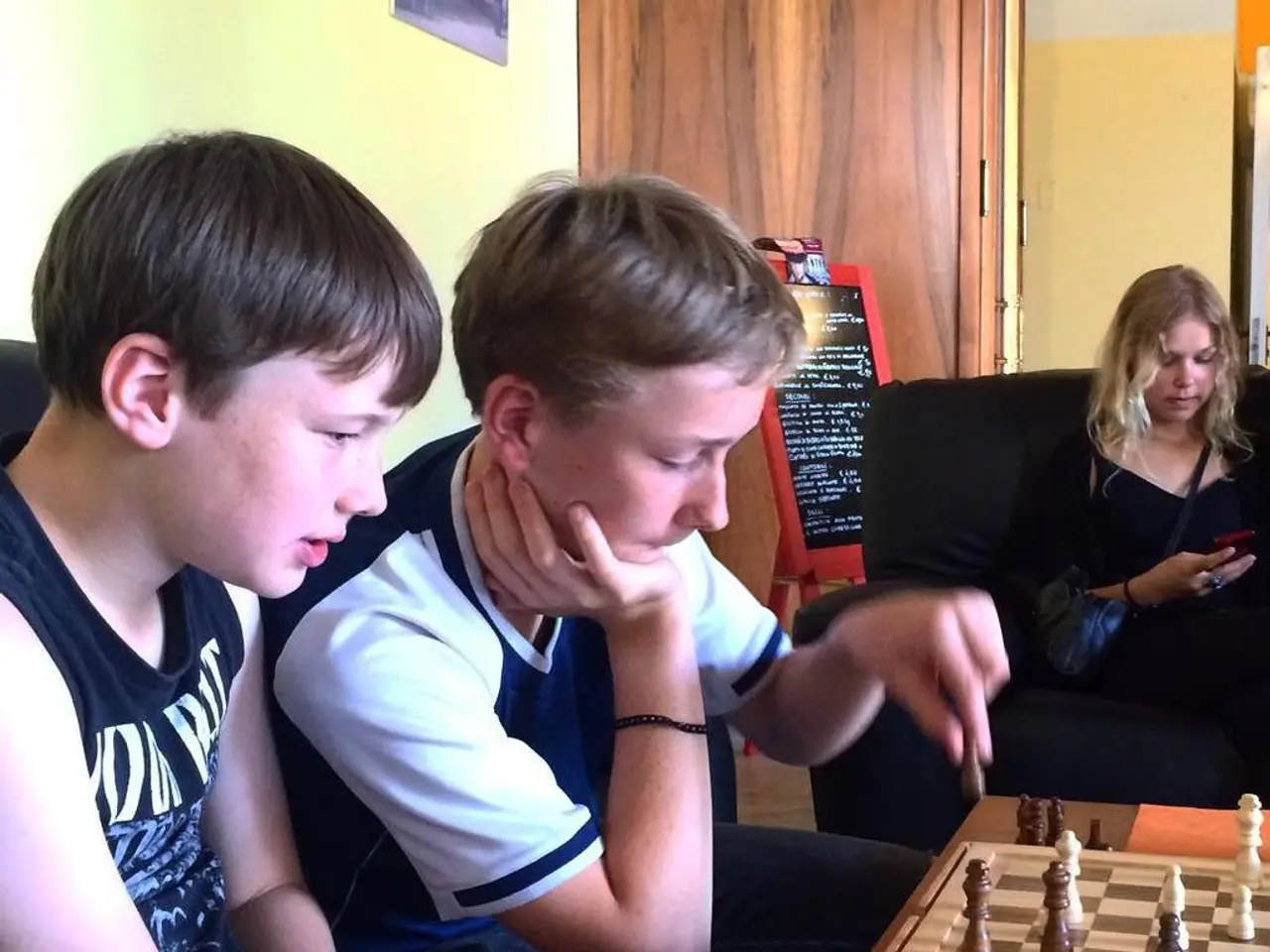 We have three people in the picture where two among them are playing the chess and the other lady...