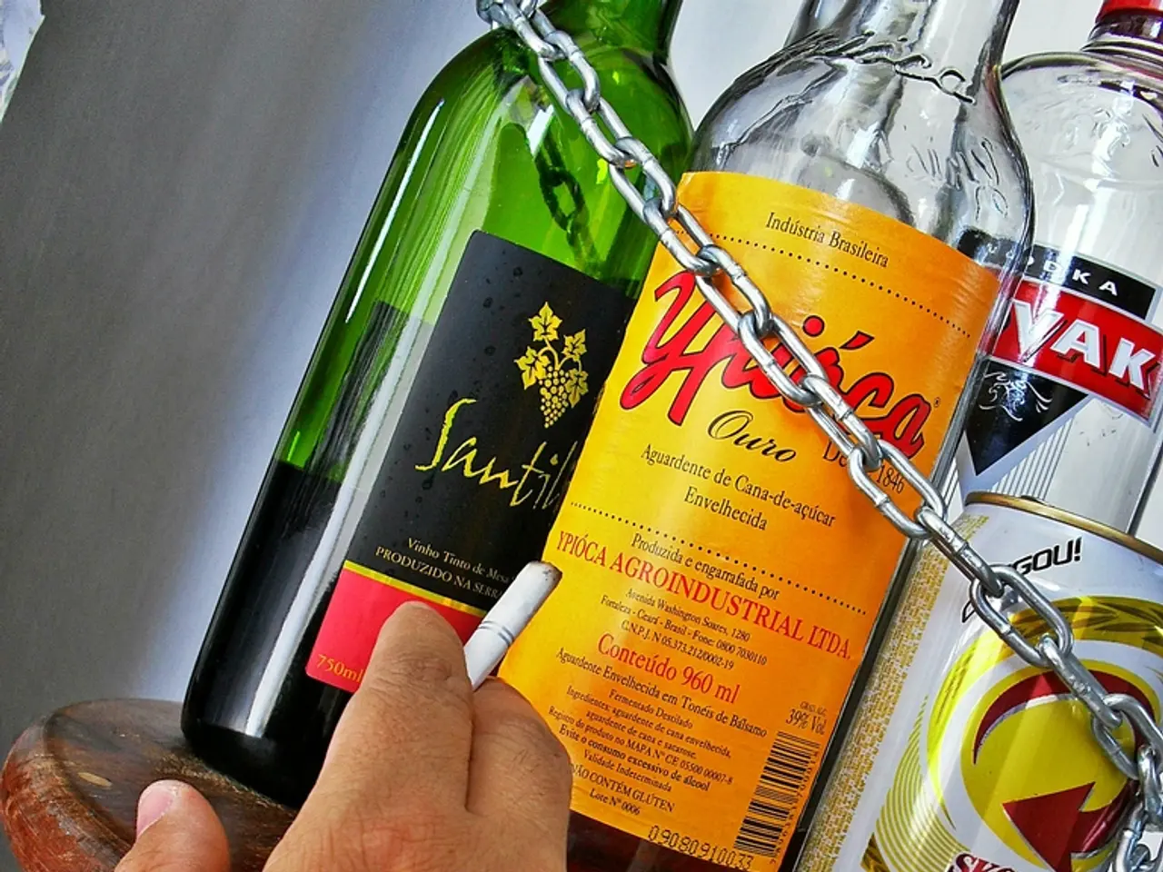 In this picture there is a small stool on which there is a cigar and some bottles and a hand in...