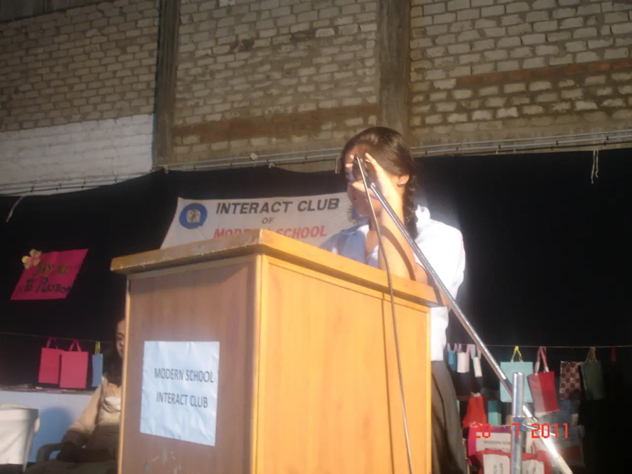 This image is clicked in a meeting. In the front, there is a podium. To the right, there is a stand...