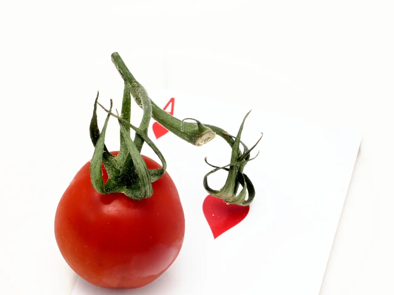 In the image we can see a playing card, on it there is a tomato, red in color.