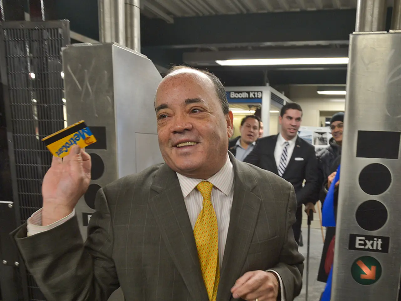 There is a person standing and holding a card. Near to him there is an exit way. On that there is a...