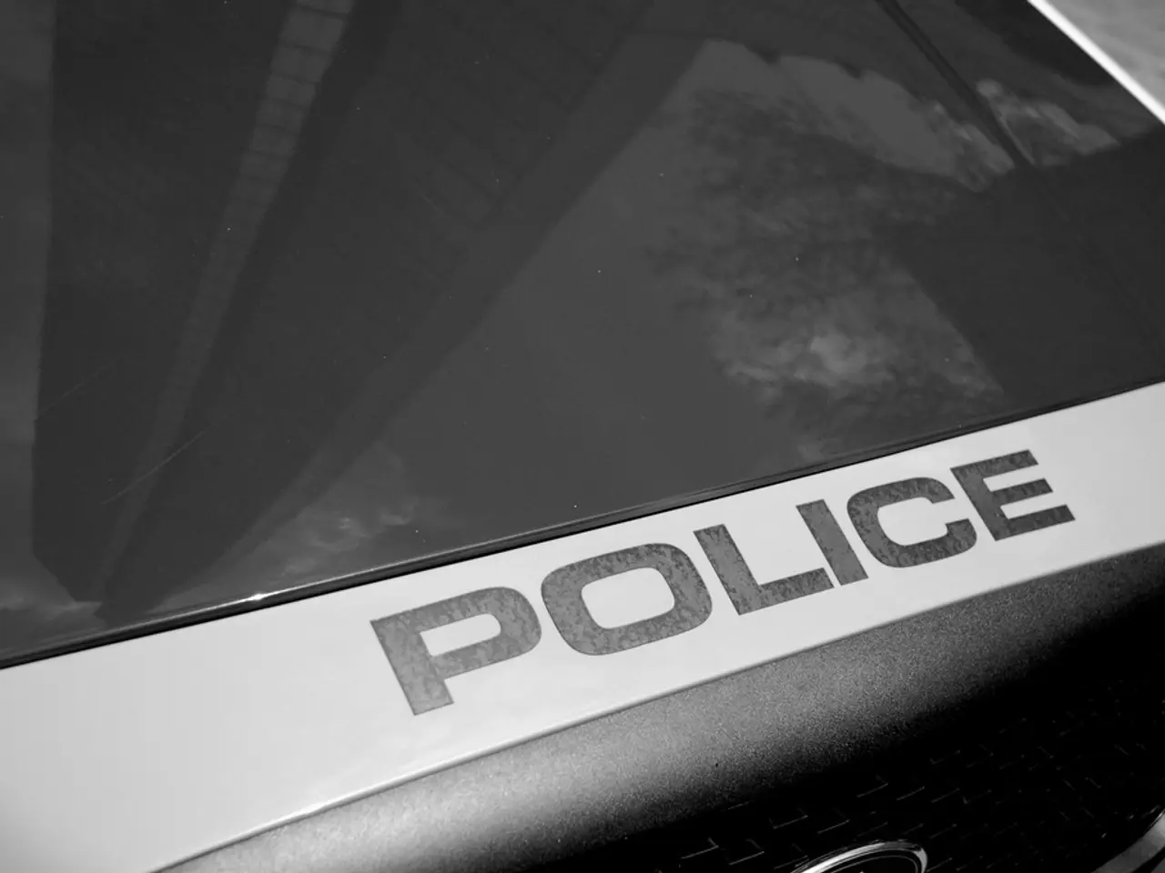 A vehicle with a board of police. On this vehicle there is a reflection of a building and tree.