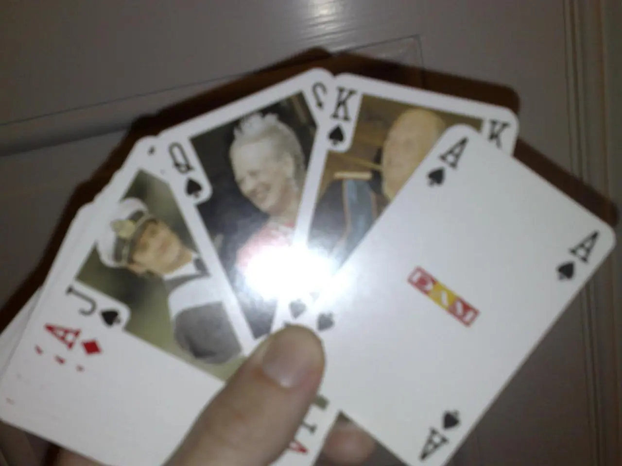 In this picture I can see the hand of a person holding cards.