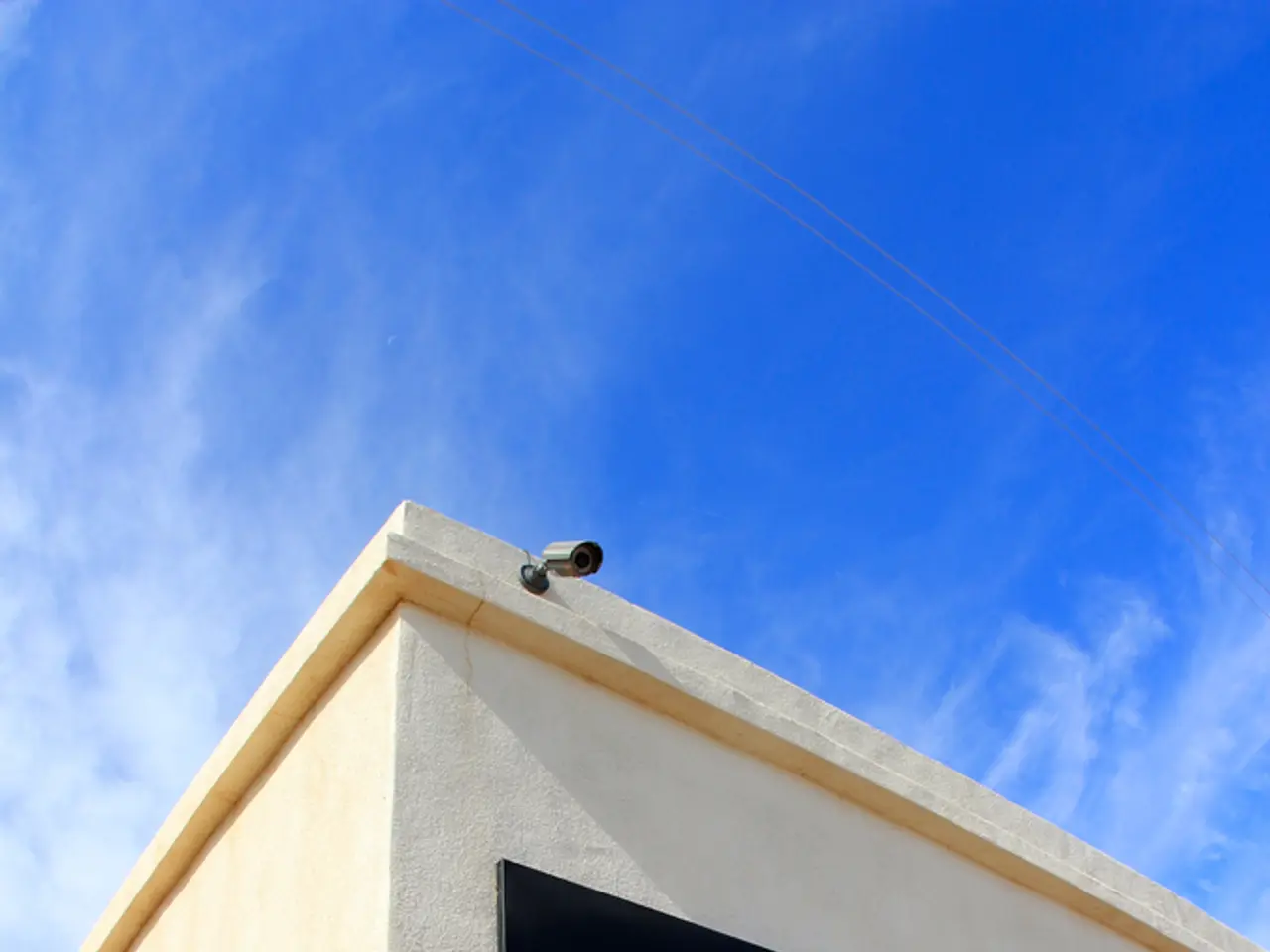 There is a name board on the wall of a building, which is having cc camera and glass doors. In the...