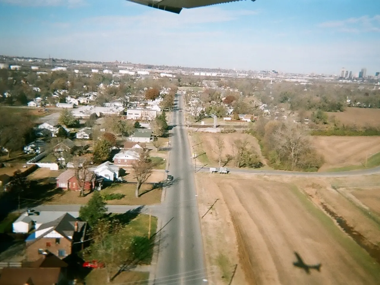 In this picture there is a top view of the town. In the front we can see some trees and small shed...