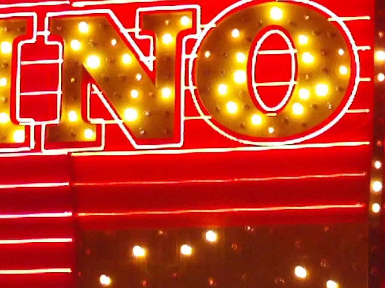 The image shows a casino sign lit up at night in front of a building, with text on the wall and...