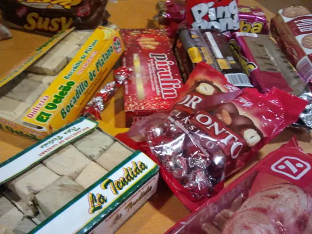 In this picture, we see a table on which sweets boxes, chocolate packets, cookies and many packets...