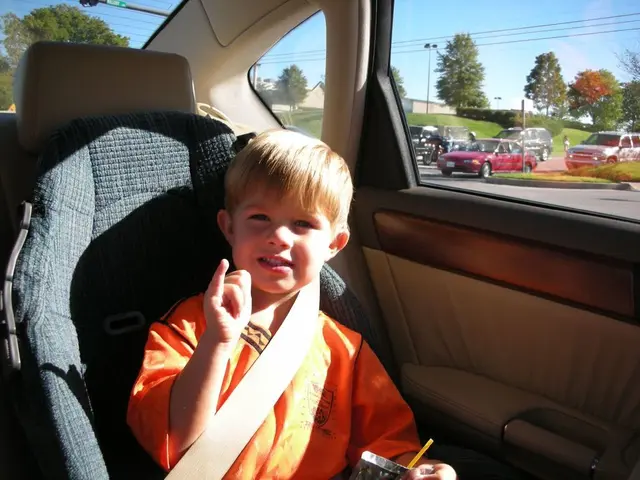 In this picture there is a boy wearing an orange shirt is holding a cover on his hand. This boy is...