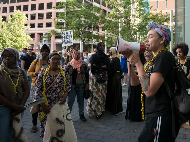 In this picture there is a woman who is wearing scarf, t-shirt, trouser and bag. She is holding a...