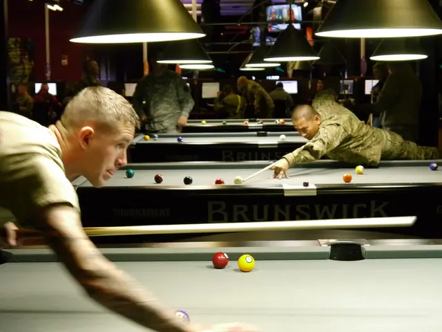 In a room there are snooker boards with balls and sticks on it. On either side of board there are...