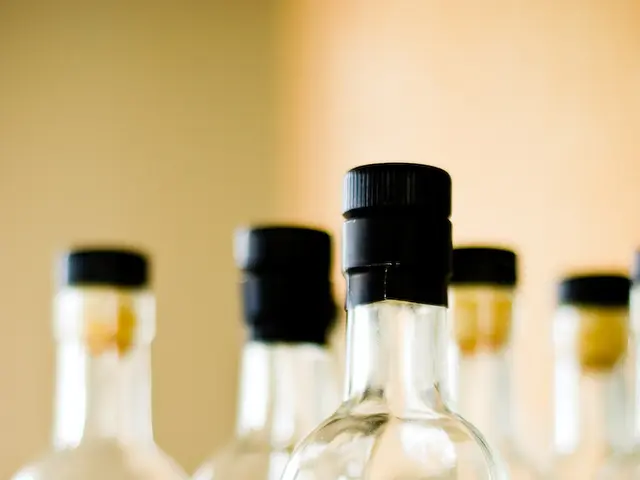 In this picture there are five alcohol bottles placed on a table. There are labels on the bottles....