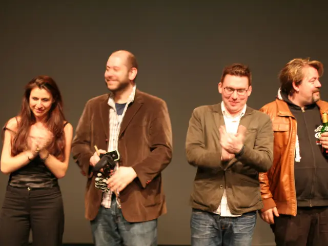 In this image we can see some persons standing, most of them wearing suits, two persons applauding...