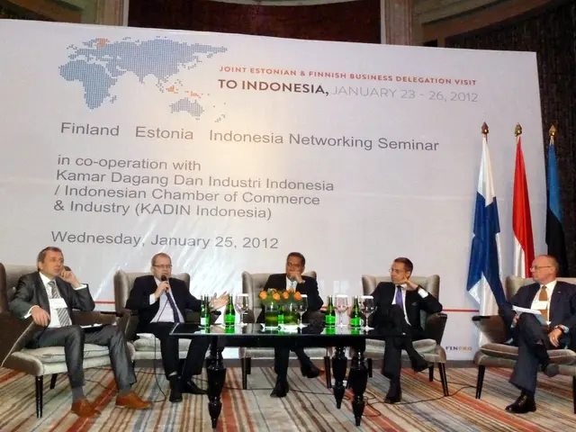 The picture is taken in a conference. In the foreground of the picture on the stage there are...