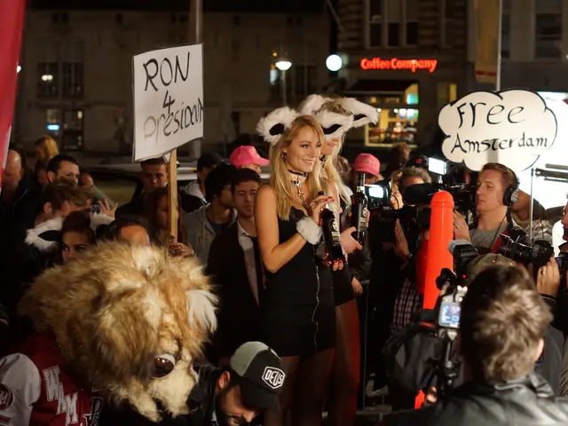 This image consists of so many people in the middle. They are holding some cards. There are...