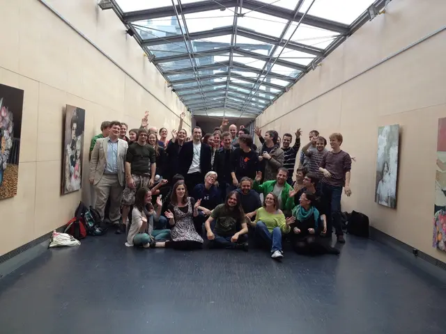 In the foreground of this image, there are group of people posing to the camera. Few are sitting...