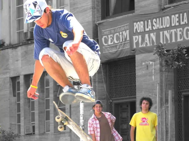 In this image there is a man performing stunt on skateboard. In the background there are persons...