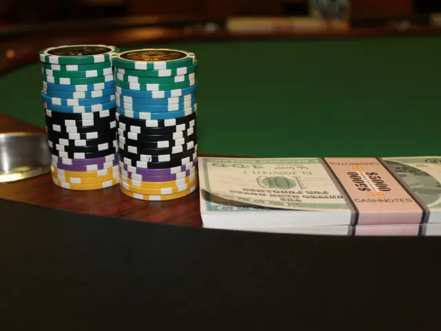 The image shows a poker table with a stack of poker chips on top of it, along with some currency...
