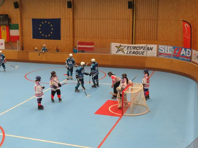 The image shows a group of people playing a game of ice hockey on a court. They are wearing helmets...