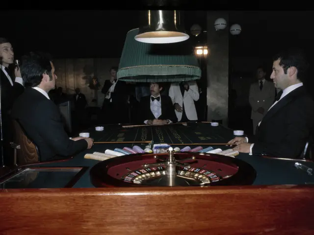 The image shows a group of men playing roulette in a casino. There are several people sitting...