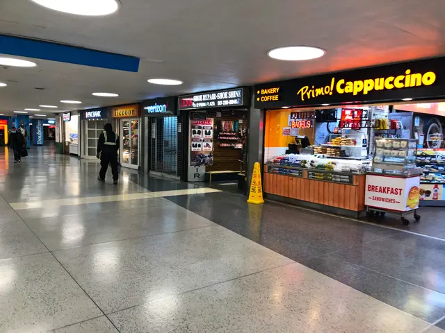 The image shows a bustling airport terminal with people walking through it. There are stores with...