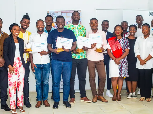 The image shows a group of people standing next to each other in a room, smiling and holding...