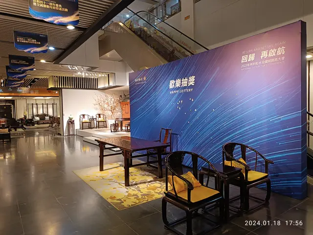 The image shows a large room with tables and chairs in it, a carpet on the floor, a banner with...