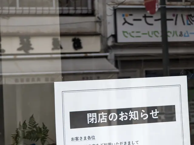 The image shows a sign in the window of a building with Chinese writing on it. Through the glass of...