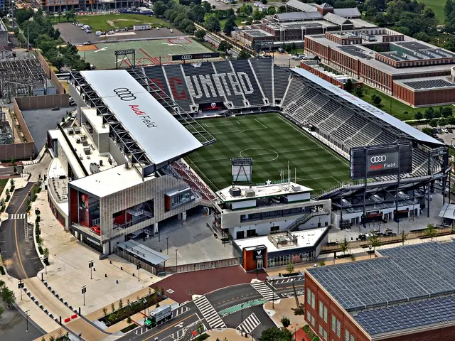 The image shows an aerial view of a soccer stadium in the middle of a city, surrounded by...