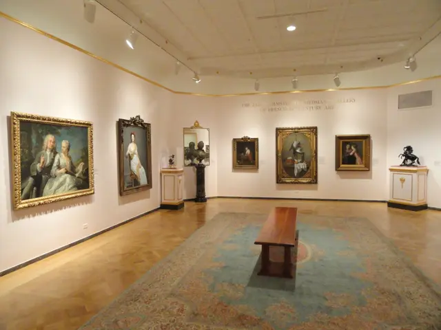 The image shows a large room filled with lots of paintings on the walls, a wooden bench on the...