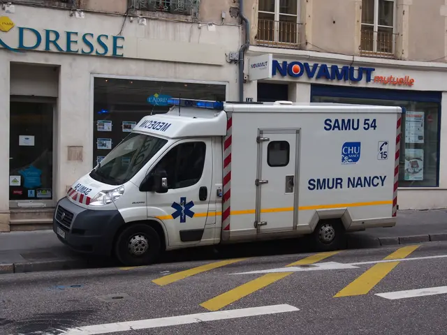 The image shows an ambulance parked on the side of the road in front of a building with windows,...