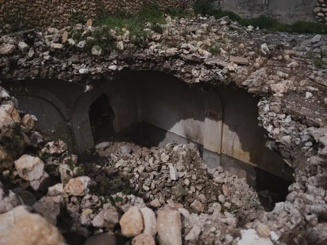 The image shows a collapsed bridge in the middle of a dirt field, surrounded by stones and grass....