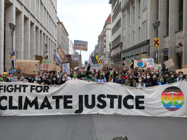 The image shows a large group of people walking down a street, holding a banner that reads "Fight...