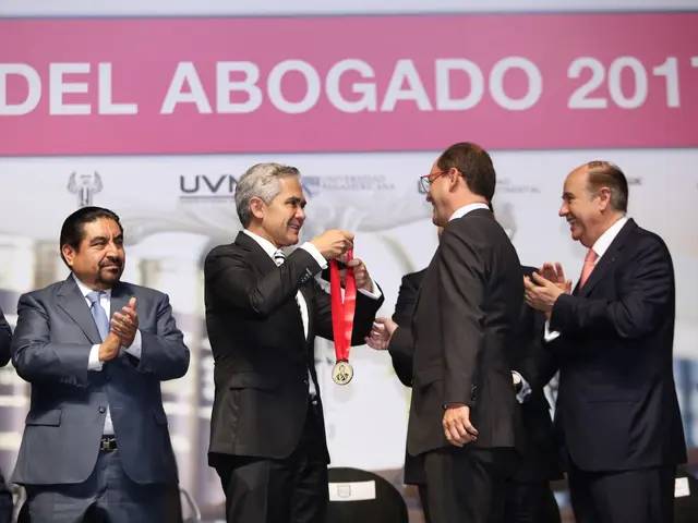 The image shows a group of men standing next to each other on a stage, with one of them holding a...