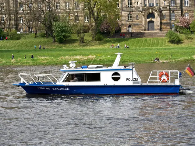 The image shows a blue and white boat traveling down a river, with a flag flying from the mast. In...