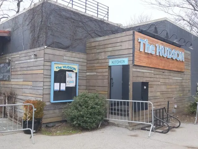 The image shows the Hudson restaurant in New York City. It is a building with a door and a board...