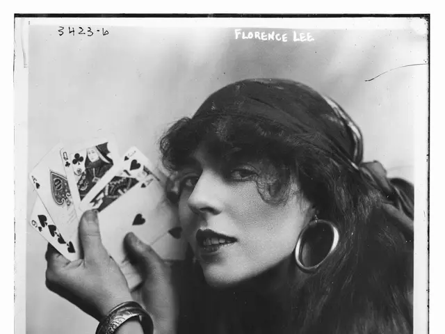 The image shows a black and white photo of a woman holding playing cards in her hand. She has a...