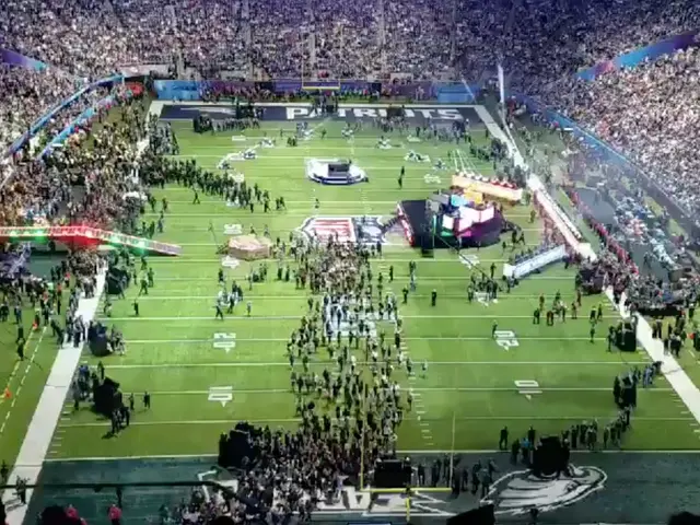 The image shows a large stadium filled with lots of people watching a football game between the New...