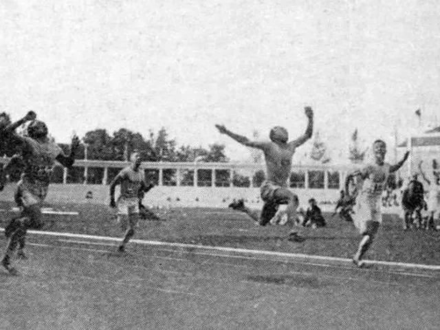 The image shows a black and white photo of a group of men playing soccer on a field. In the...