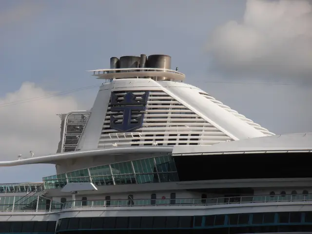The image shows Royal Caribbean's Allure of the Seas, a large white and blue cruise ship, with a...