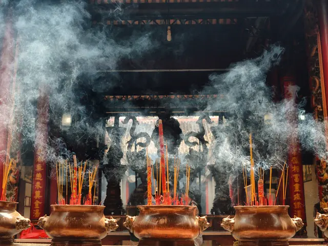 The image shows a group of incense sticks burning in a Buddhist temple, with smoke billowing out of...